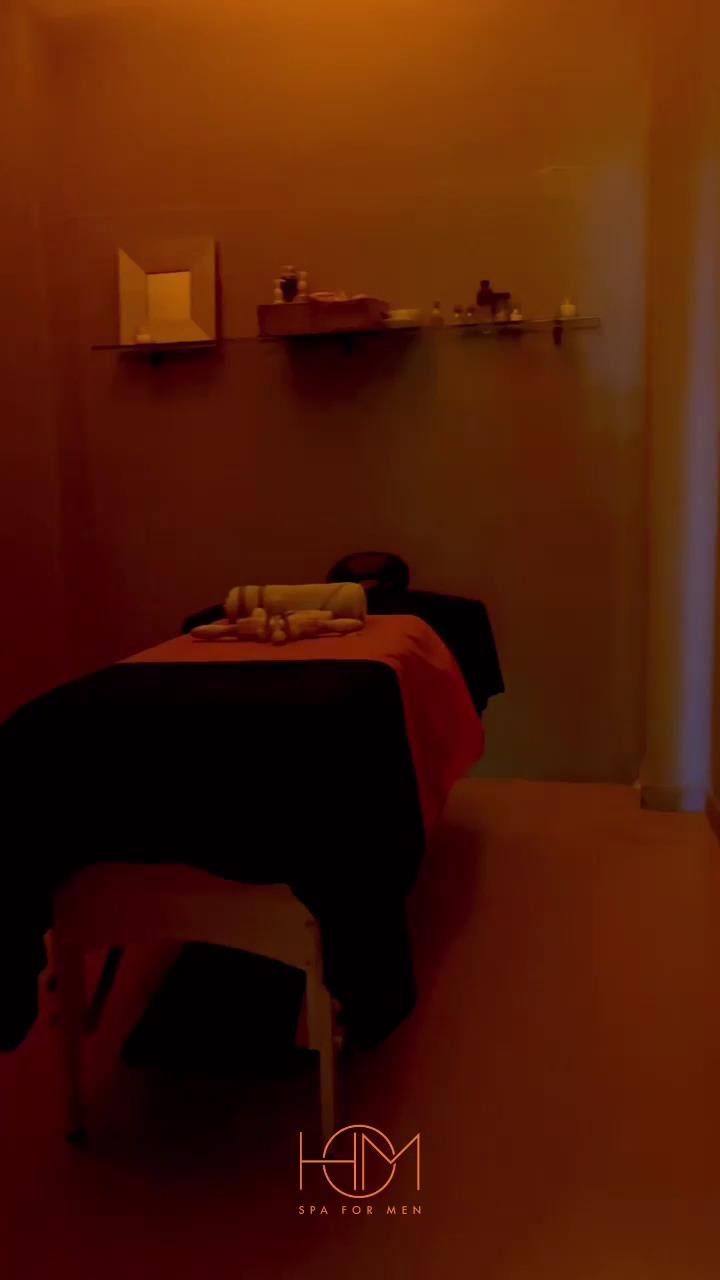 Cabina de masaje con luz cálida y el monograma HOM en la pared