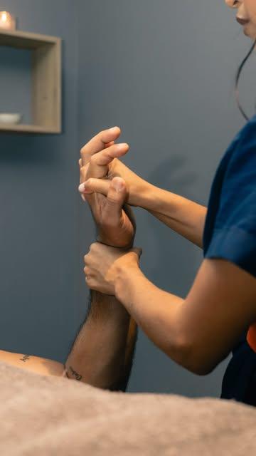 Terapeuta trabajando la mano de un cliente